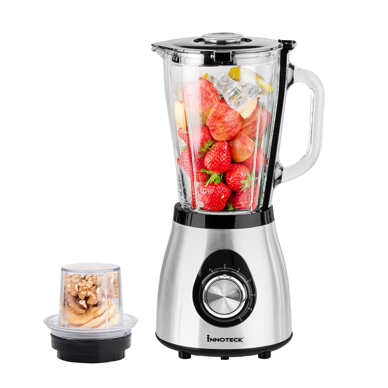 A silver speed blender and grinder set with a blender jar and a grinder attachment, filled with fruits and nuts.