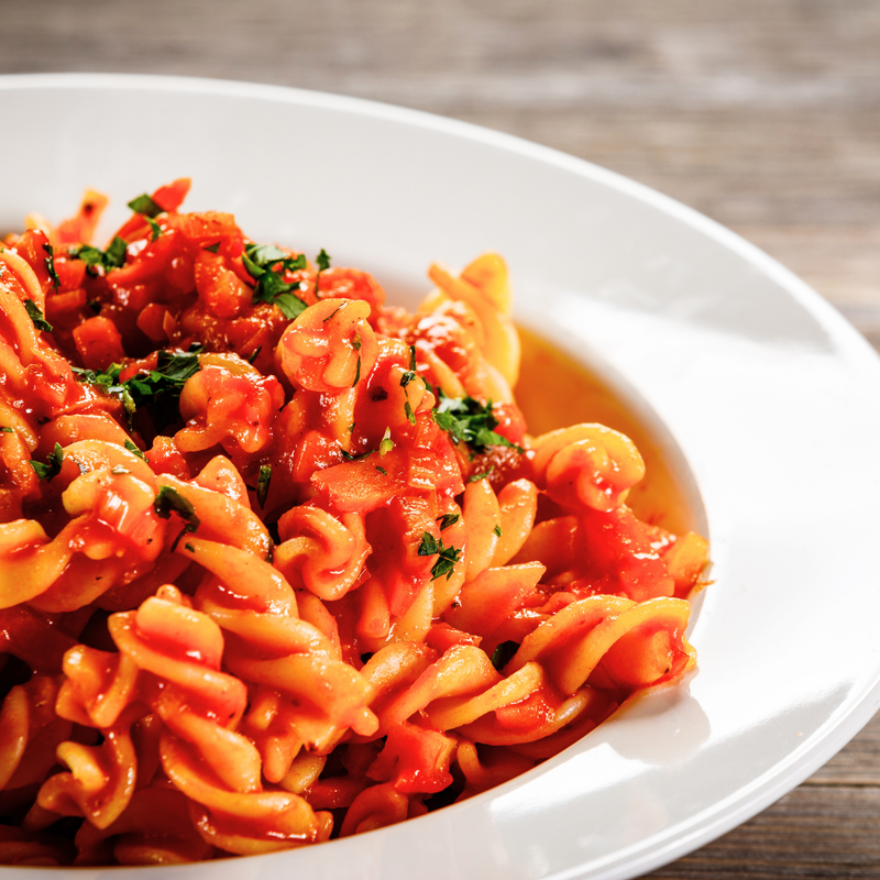 Pasta dish with tomato sauce and herbs on a white plate